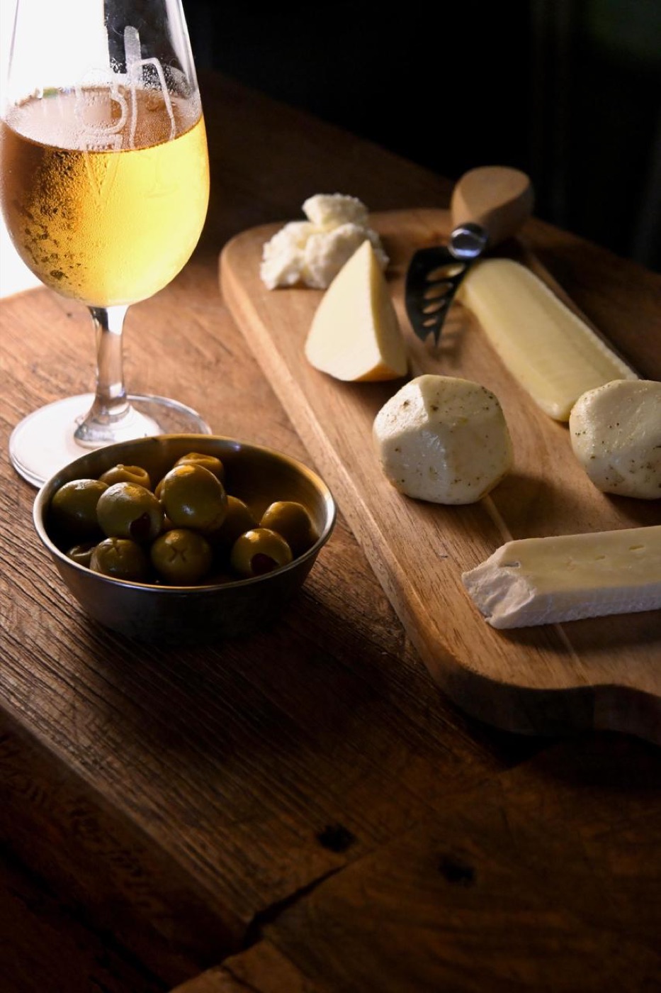 Tabla de quesos con aceitunas y copa de vino
